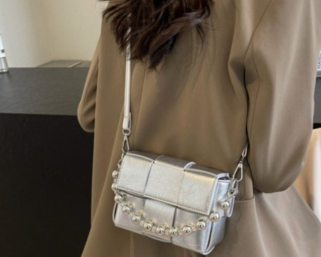 wearing a korean style silver handbag with round embellishments in an indoor setting