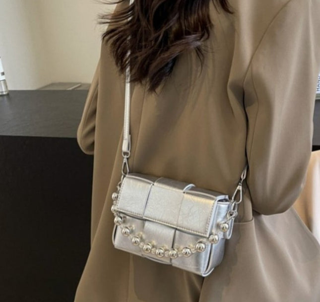 wearing a korean style silver handbag with round embellishments in an indoor setting