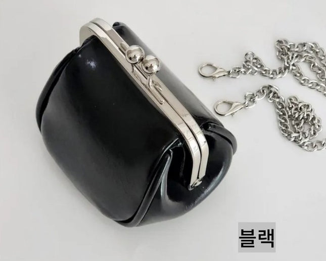 Cute mini black handbag with silver clasp and chain on a white background