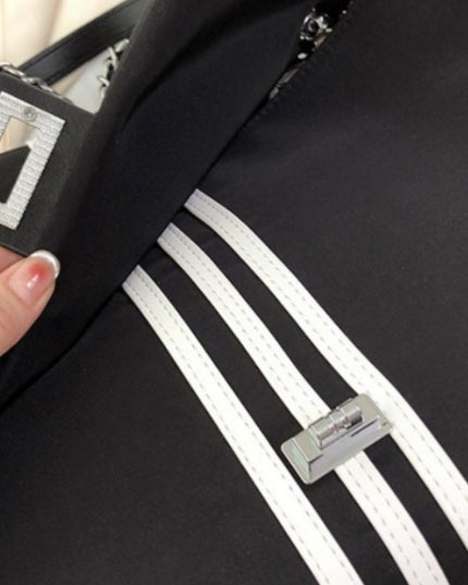 Black stylish bag with white stripes and a visible brand logo, held by a hand.